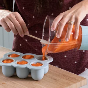 Modelo guardando una mezcla de verduras en los tazones de almacenamiento con bandeja de la nutribullet® Baby