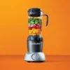 nutribullet® Select 2.0 color gris - Licuadora con alimentos en fondo naranja