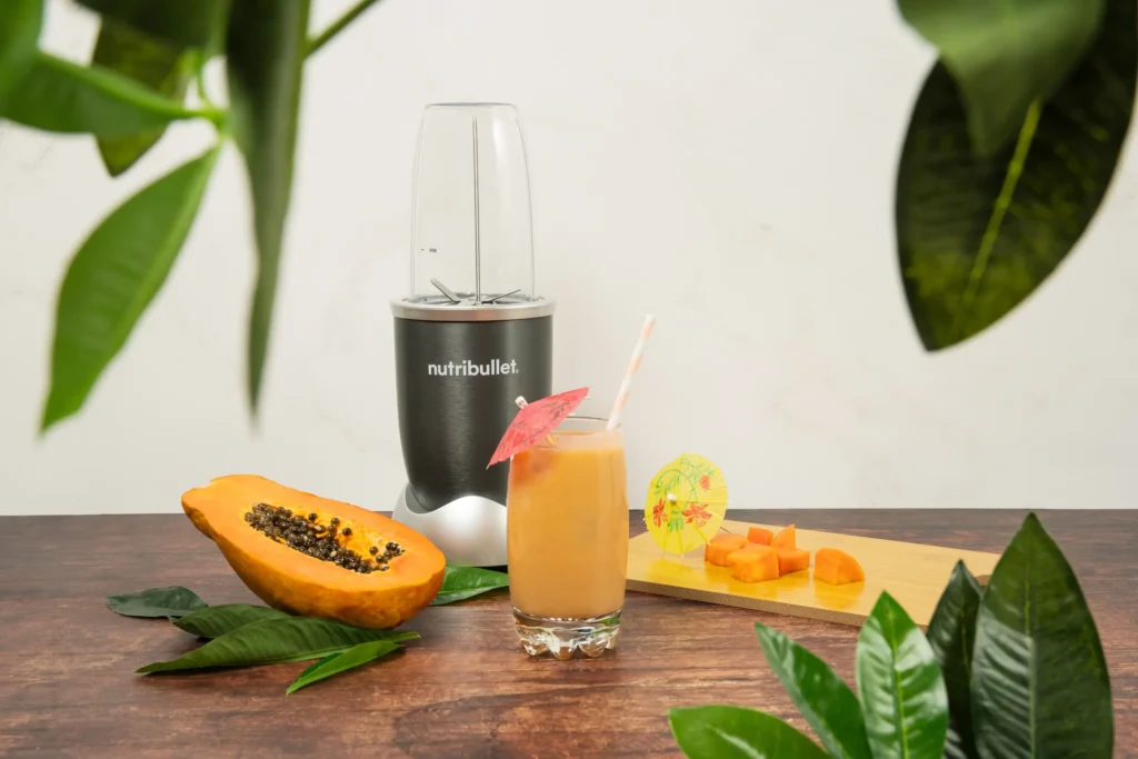 Papaya Paradise Smoothie, una nutribullet® 600W gris junto con ingredientes de papaya y un vaso del smoothie