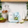 nutribullet® Baby Steam & Blend en una encimera de cocina con elementos de cocina alrededor y trozos de pera en el interior del tazón