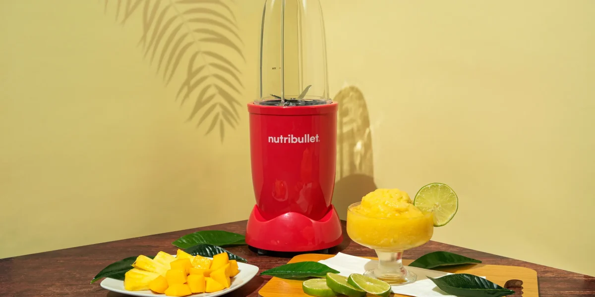 Sorbete Tropical, una nutribullet® 600W Rubí de la Colección Glossy junto con pedazos de frutas cortadas y una copa con el sorbete
