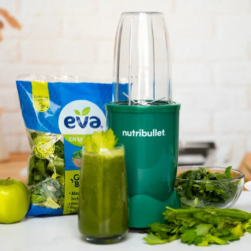 Jugo Verde con Ensalada EVA Green Boost, bolsa de ensalada EVA lista para comer junto a una nutribullet® 600W Esmeralda de la Colección Glossy, frutas y verduras de la receta, y un vaso del jugo final
