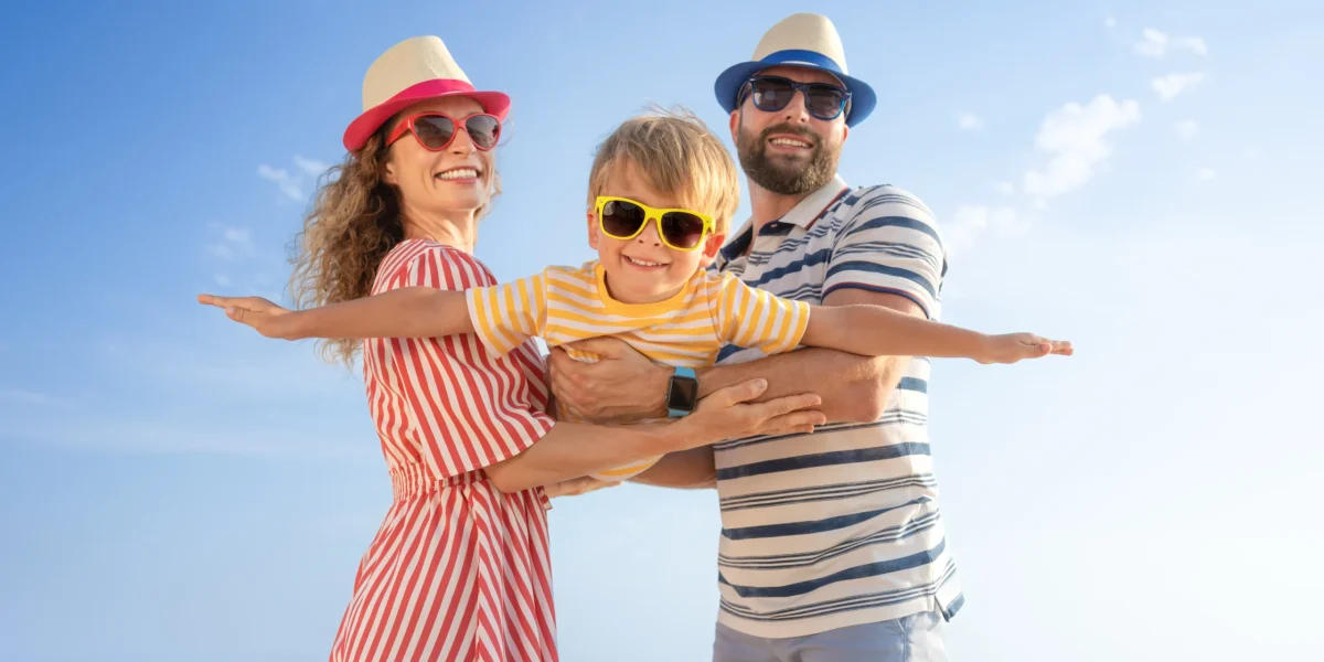 familia-feliz-divirtiendose-playa-madre-padre-sosteniendo-su-hijo-contra-fondo-azul-mar-cielo-concepto-vacaciones-verano