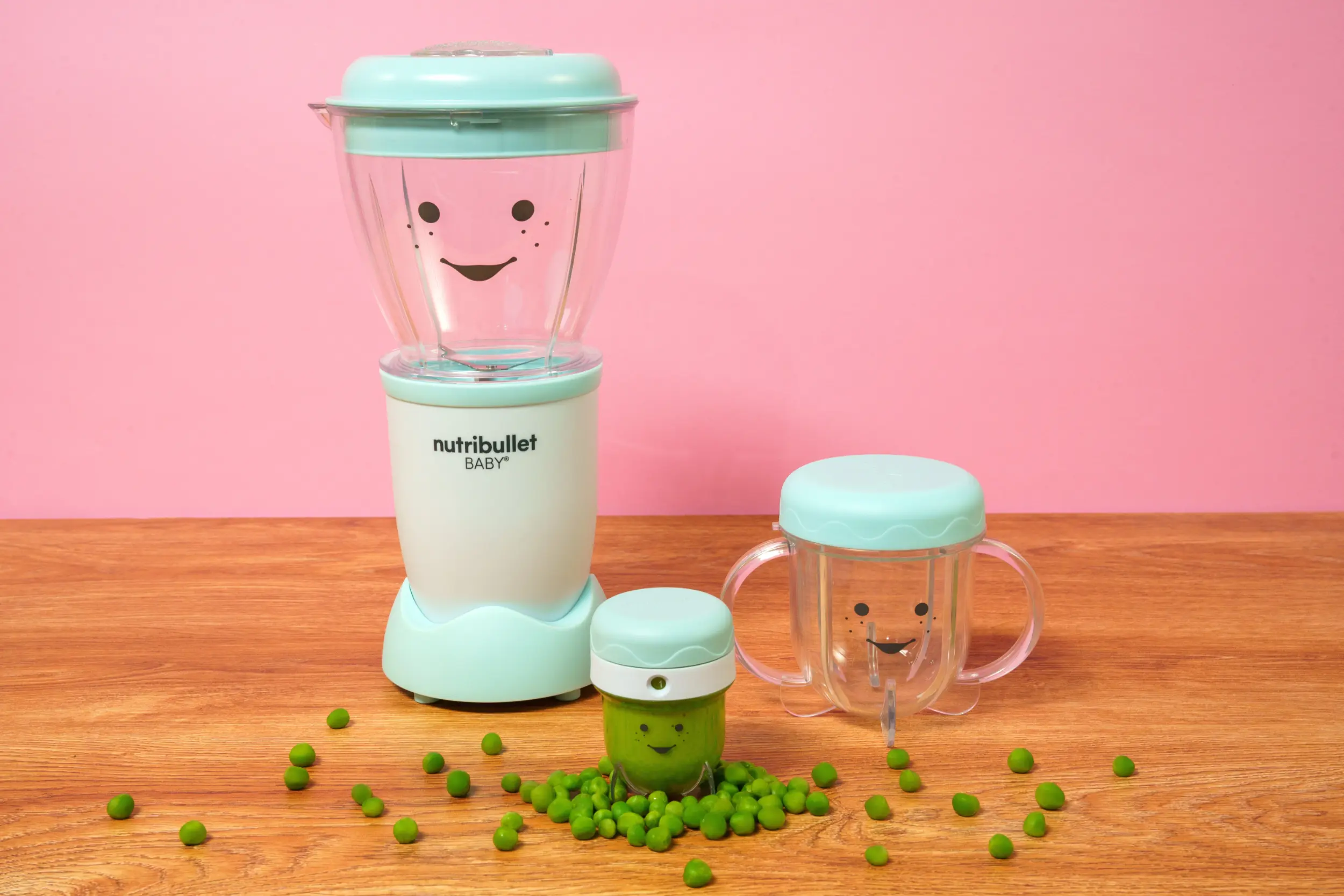 nutribullet® Baby con sus accesorios sobre una mesa, con el contenedor de guardado lleno de puré de chícharo