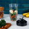 Vaso Tritan Renew con ingredientes como kale, plátano y almendras para preparar un smoothie, con una aspa al lado