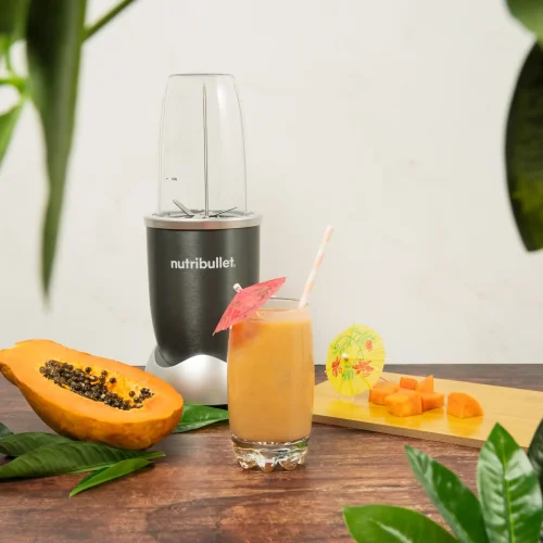 Papaya Paradise Smoothie, una nutribullet® 600W gris junto con ingredientes de papaya y un vaso del smoothie