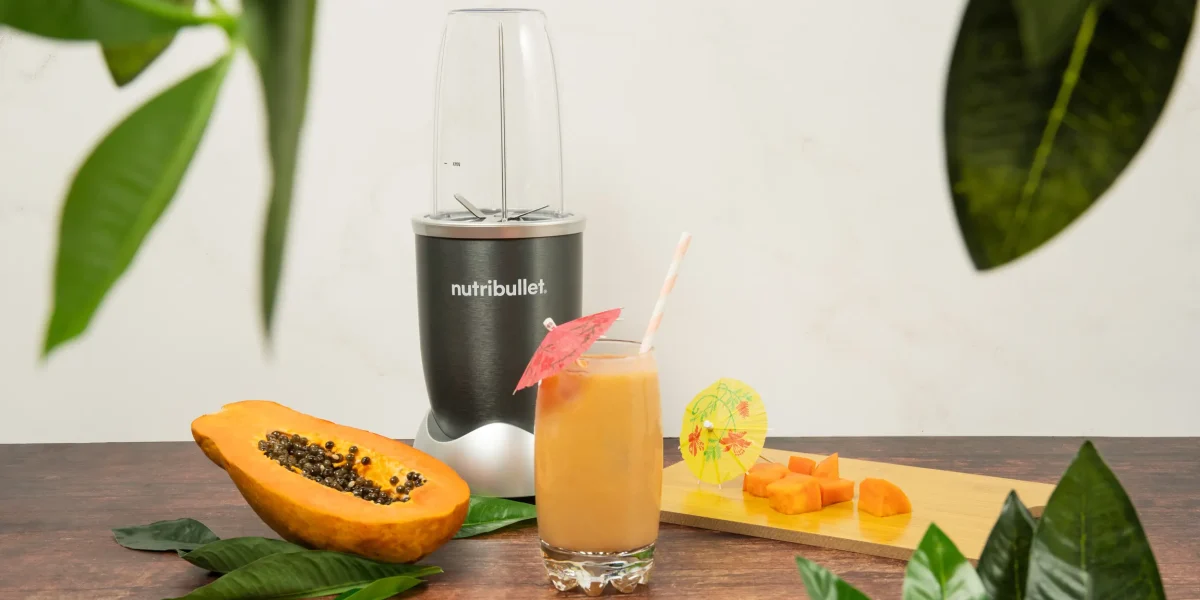 Papaya Paradise Smoothie, una nutribullet® 600W gris junto con ingredientes de papaya y un vaso del smoothie